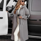 Women’s long hooded cardigan coat in grey beside white vehicle, soft knit sleeves creating minimalist chic warmth for everyday outfits