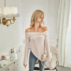 Women's beige off shoulder knit top paired with crossbody bag in softly lit bedroom setting.