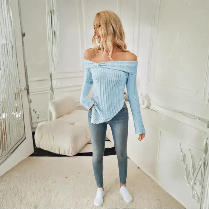 Full view of light blue off shoulder knit top styled with skinny jeans and white sneakers indoors.