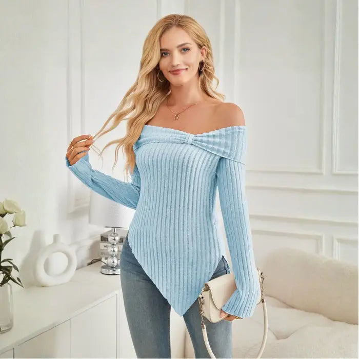 Model smiling in light blue off shoulder knit top with long sleeves and casual accessories.