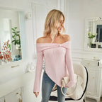 Women's off shoulder knit top in pink styled with handbag and blue jeans for a chic look.