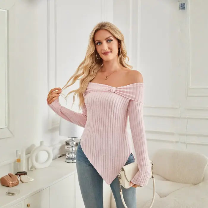 Model wearing women's off shoulder knit top in light pink, styled with accessories and denim.
