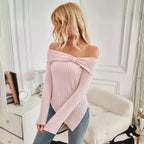 Editorial room shot of pink women's off shoulder knit top styled with minimal decor.