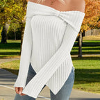 Women's off shoulder knit top in white worn outdoors, ribbed design with knot detail and long sleeves.