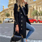 Womens Overcoat in black with gold buttons, styled with jeans and handbag on a city street.
