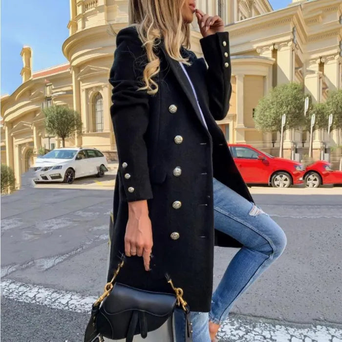Womens Overcoat in black with gold buttons, styled with jeans and handbag on a city street.