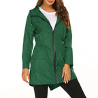Womens raincoat in green with front zipper and pockets worn over a white top.