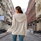 Women's Ribbed Hoodie shown from back view on cobblestone city street with fire escapes.