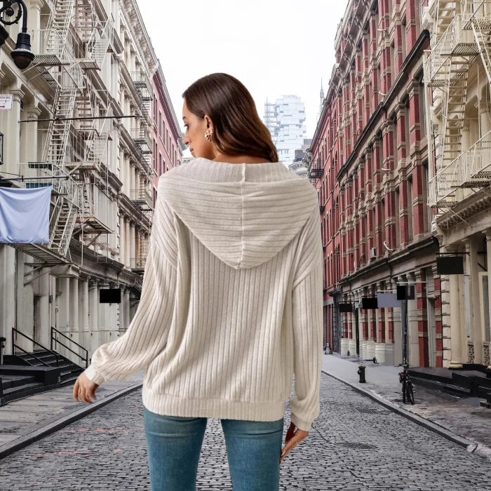 Women's Ribbed Hoodie shown from back view on cobblestone city street with fire escapes.