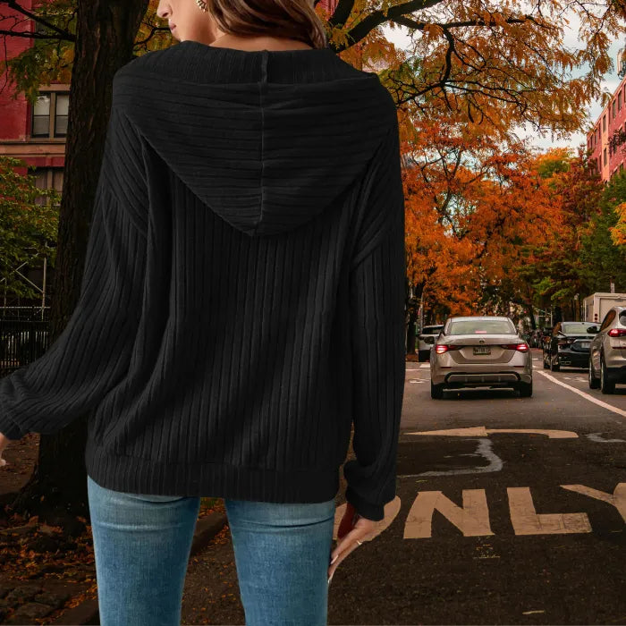 Women's Ribbed Hoodie in black from back view, styled with jeans on a tree-lined city street in fall.