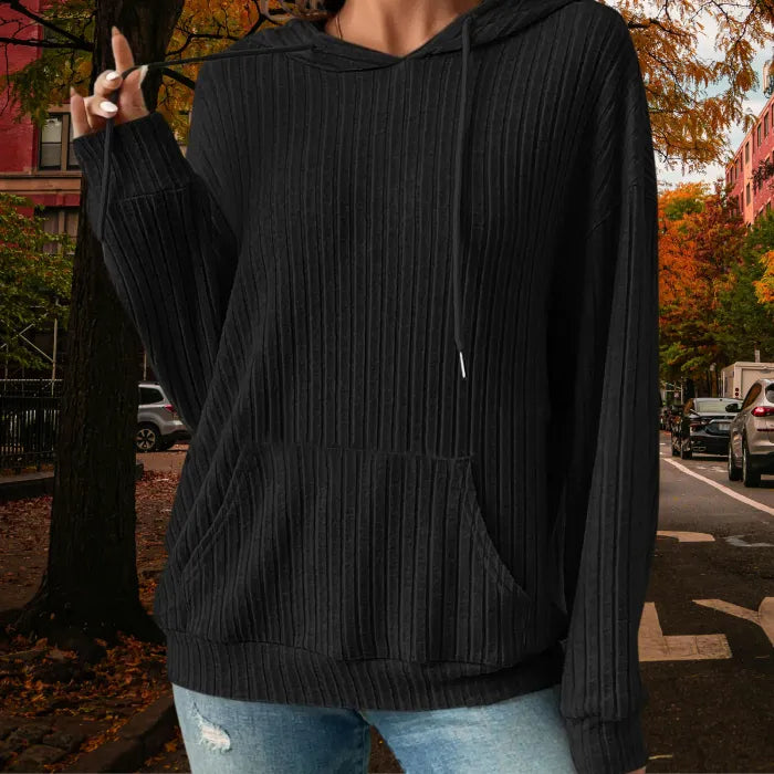 Women's Ribbed Hoodie in black with textured ribbed fabric and drawstring, styled outdoors on autumn street.
