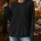 Women's Ribbed Hoodie in black with textured ribbed fabric and drawstring, styled outdoors on autumn street.