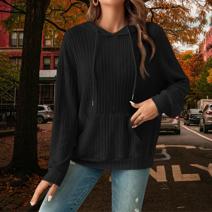 Women's Ribbed Hoodie in black styled with ripped jeans for a casual fall outfit on a city street.