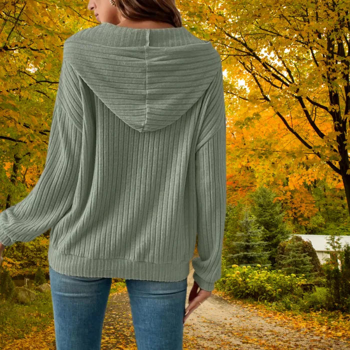 Women's Ribbed Hoodie in green shown from the back in a forest path with fall leaves.