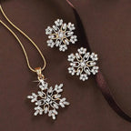 Women’s snowflake necklace and earring set in gold with sparkling crystal snowflake design displayed on brown background for elegant winter jewelry