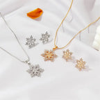 Women’s snowflake necklace and earring set in gold and silver with matching crystal snowflakes displayed on silk for festive winter gifting