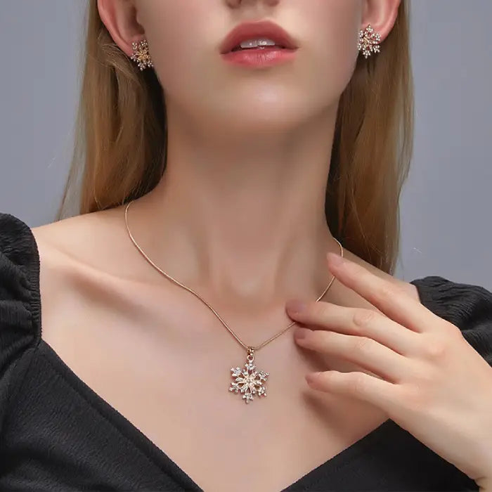 Women’s snowflake necklace and earring set worn close-up, showing gold crystal snowflake pendant and matching earrings for winter elegance