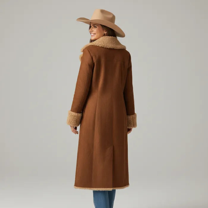 Woman wearing a brown coat with fur trim and a matching hat on a gray background