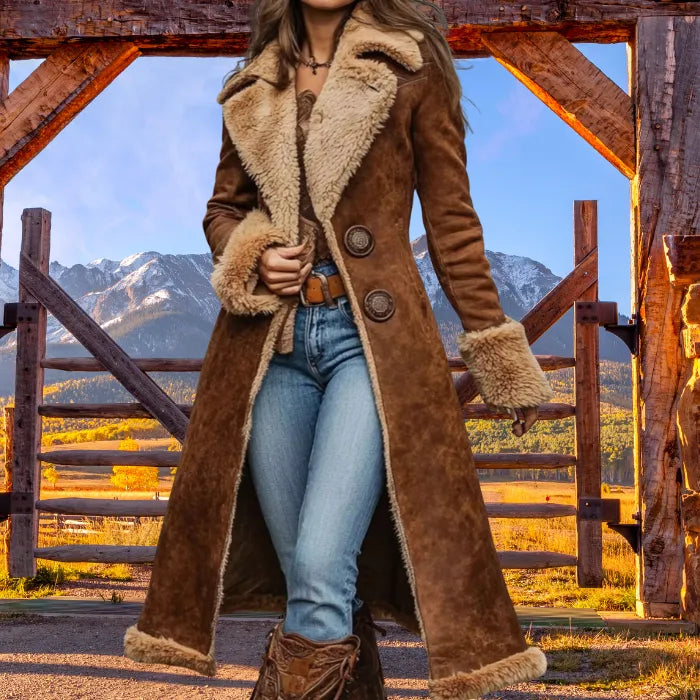 Person wearing a brown shearling coat with mountains in the background