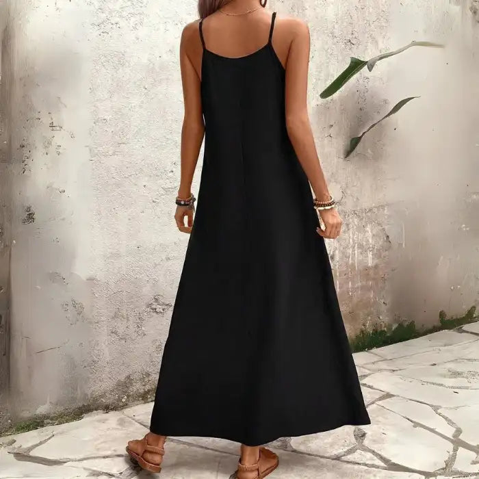 Women's tropical leaf print maxi dress showing plain black back and adjustable spaghetti straps.