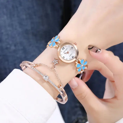 Women's watch bracelet set with blue flower design and matching crystal bracelet on wrist.