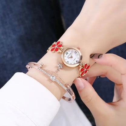 Women's watch bracelet set with red flower design worn on the wrist.