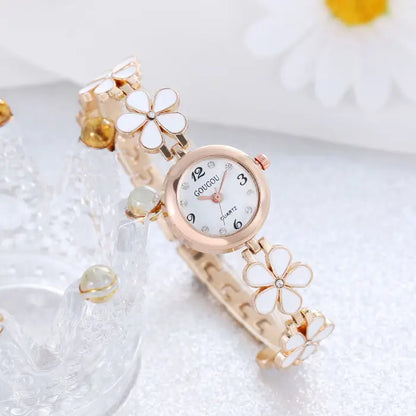 Women's watch bracelet set with white flower design and rose gold accents.