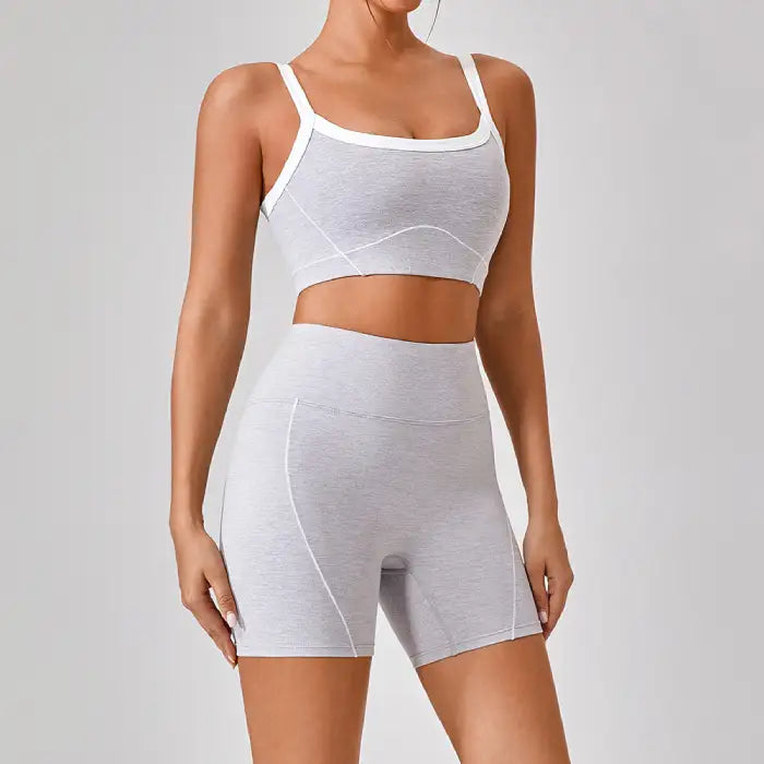 Women's workout set in heather gray featuring sports bra and high-waisted shorts with white contrast trim and contour lines