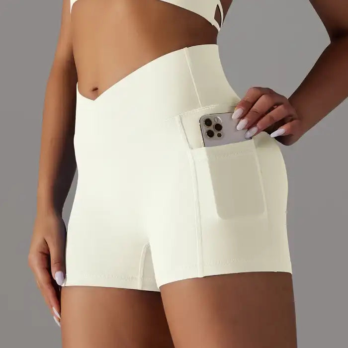 Womens yoga shorts in cream with V front waistband and side phone pocket for gym or athleisure looks.
