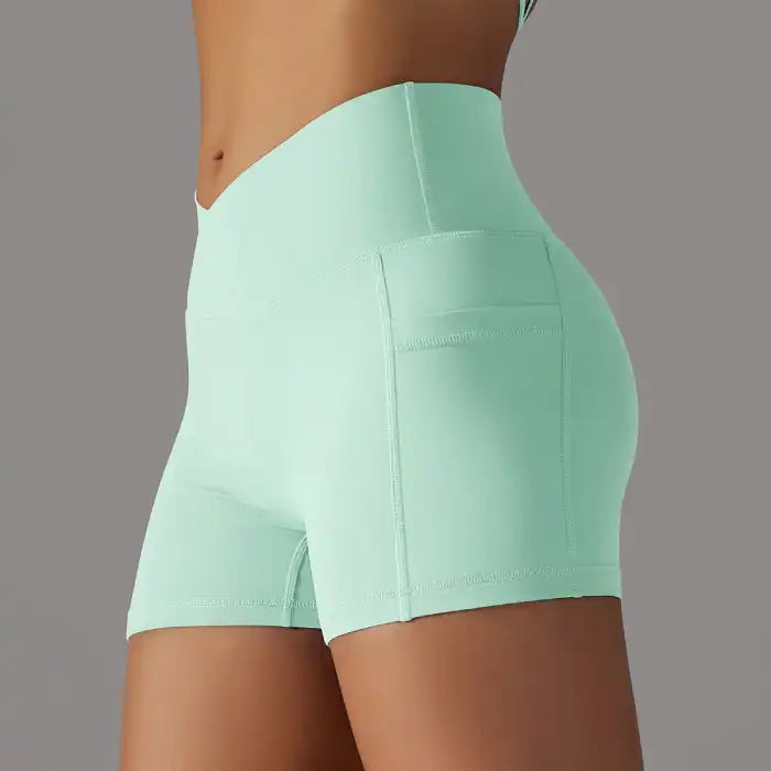 Womens yoga shorts in mint green with soft texture, side pocket, and crossover waistband design