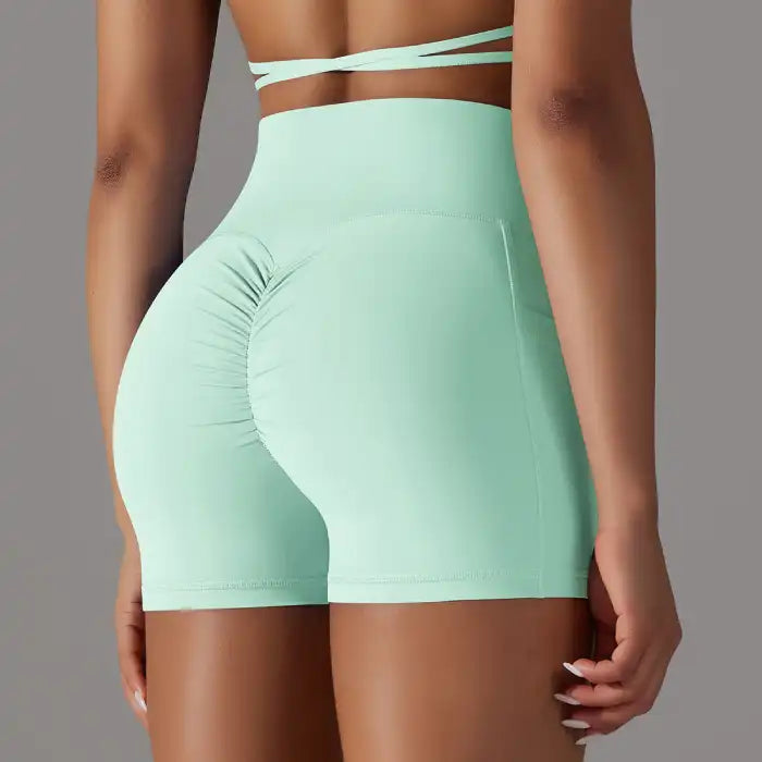 Womens yoga shorts in mint green with ruched scrunch back and supportive high waist for active wear.