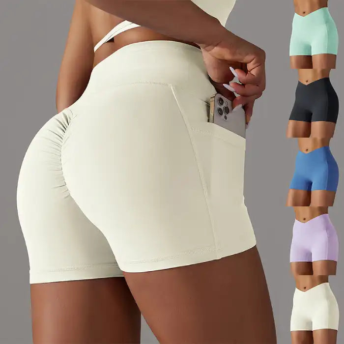 Womens yoga shorts in cream with scrunch detail and side pocket, shown with phone for function display.