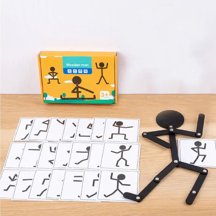 Wooden stick figure toy arranged with pose cards and packaging on a table.