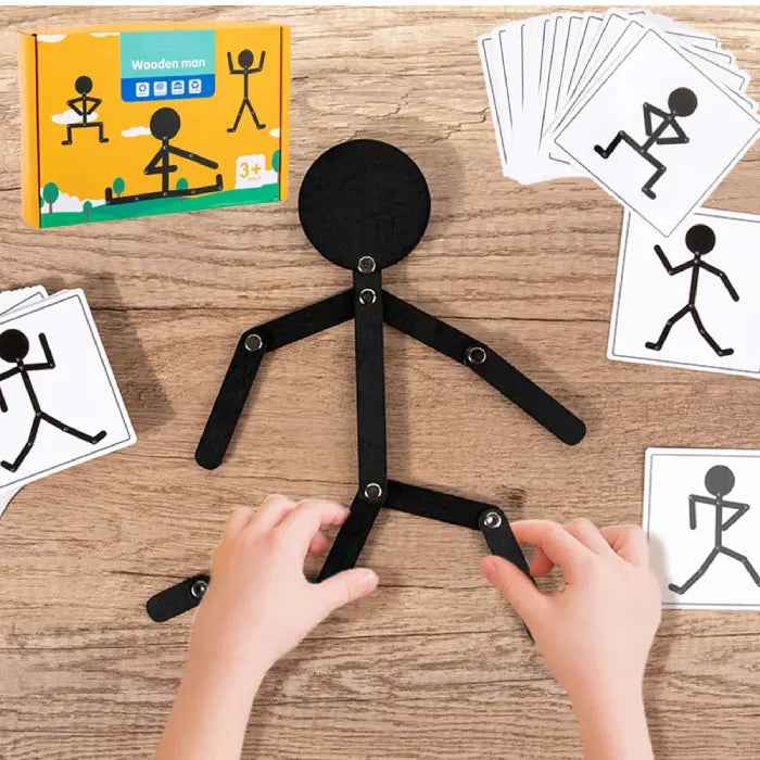 Wooden stick figure toy with pose cards and packaging displayed on a wooden table.