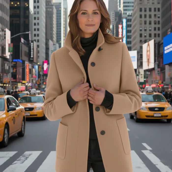 Wool pea coat in camel worn by a woman standing in a busy urban street with taxis.