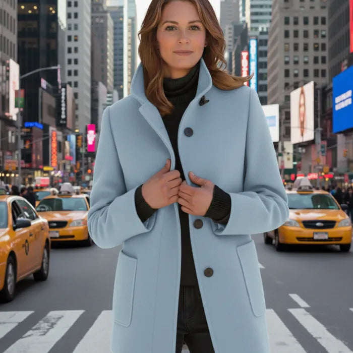 Wool pea coat in light blue worn by a woman in a city with taxis and tall buildings.