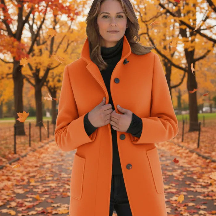 Wool pea coat in bright orange worn by a woman in an autumn park with falling leaves.