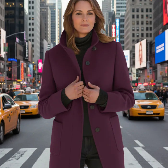 Wool pea coat in plum worn by a woman standing in a busy city street with taxis.