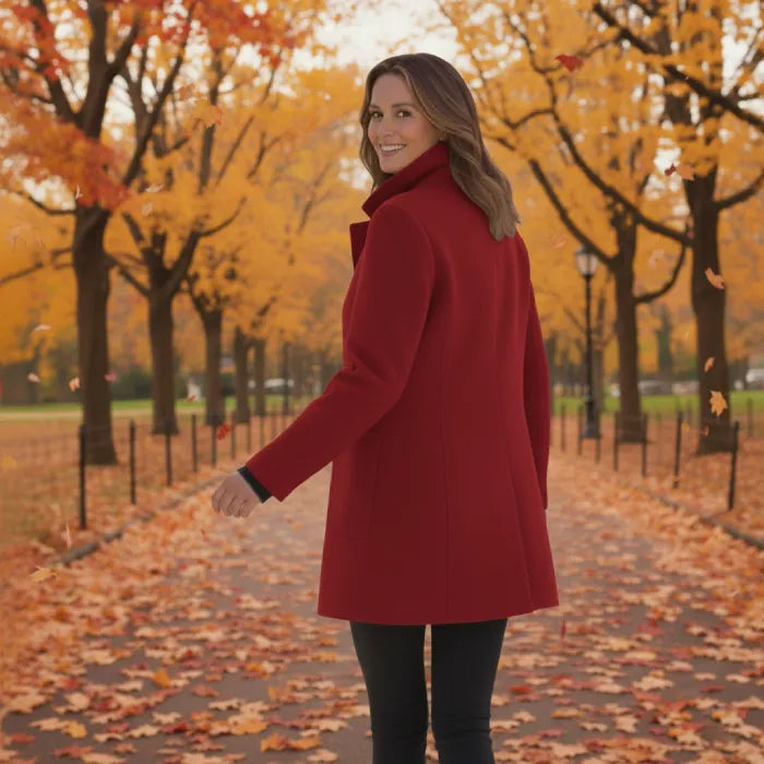 Woman wearing a red wool pea coat shown from behind while walking in an autumn park.