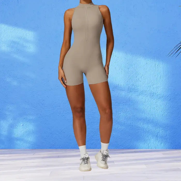 workout romper in neutral beige with front zipper and mock neck design against bright blue background for versatile fitness wear