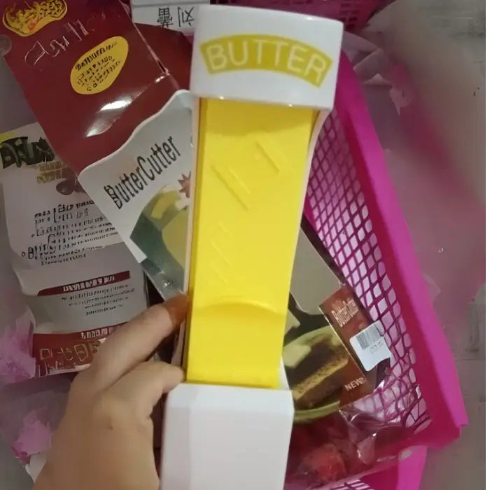 Close-up of a yellow butter cutter with packaging, displayed in a pink basket.