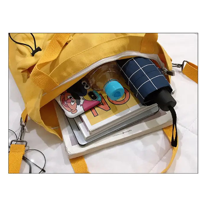 Inside view of yellow canvas tote showing books, water bottle and storage capacity