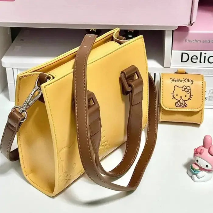 Yellow Hello Kitty handbag with detachable pouch and brown straps, ideal for versatile daily use.