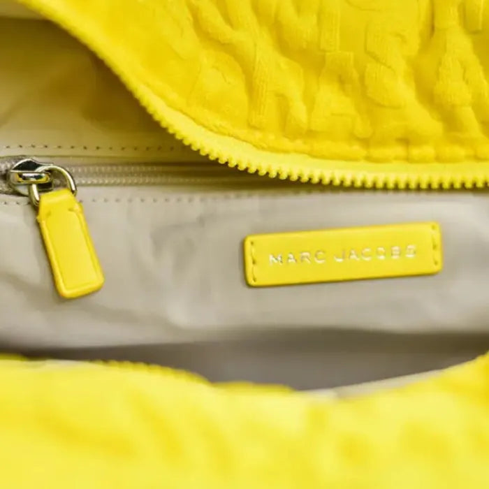 Interior of Marc Jacobs tote bag with yellow tag and zipper, offering a spacious compartment for essentials.