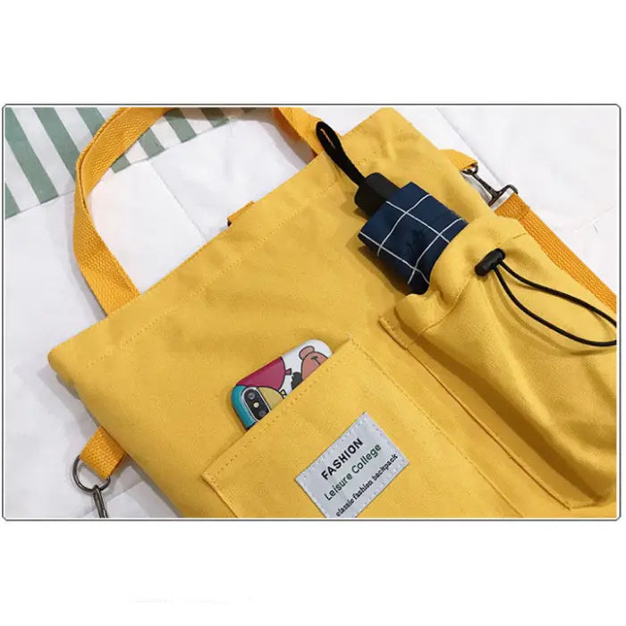 Detailed view of yellow tote bag's exterior pockets and fashion label