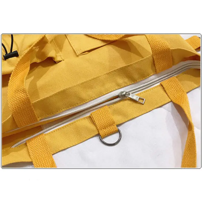 Detailed view of yellow tote bag's exterior pockets and fashion label