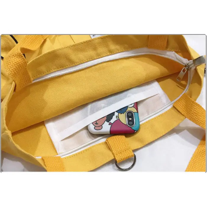 Interior view of yellow tote bag showing phone pocket and white lining