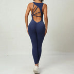  Yoga-jumpsuit in navy with deep V-back and geometric strap layout for stylish workout or gym wear.