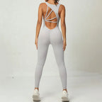 Yoga jumpsuit in light grey featuring open back with crisscross straps for flexible activewear style.
