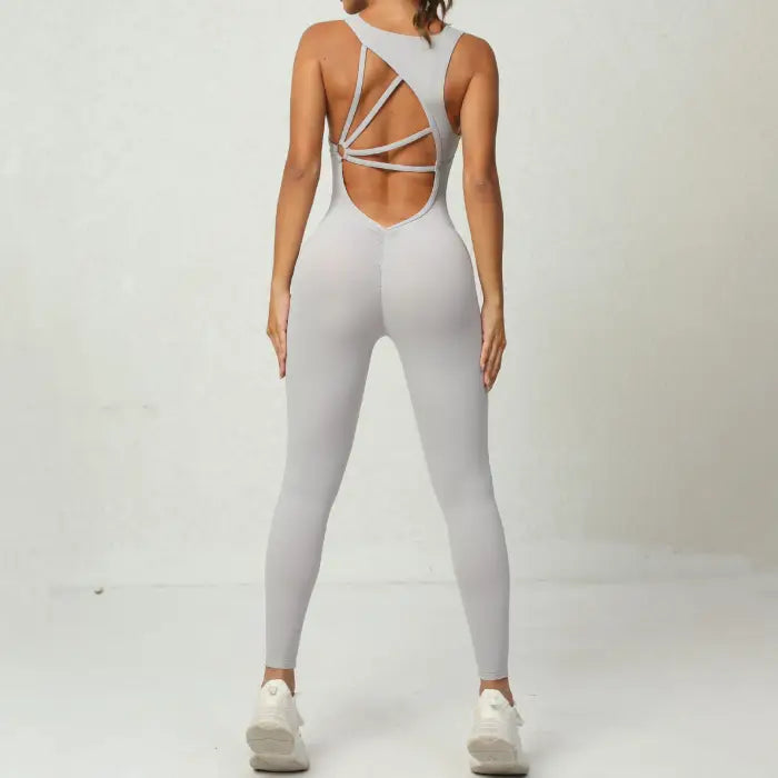 Yoga jumpsuit in light grey featuring open back with crisscross straps for flexible activewear style.